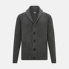 View 1 of product The Turnbull & Asser Shadow Grey Cashmere Shawl Collar Cardigan features ribbed detailing, a front button closure, and two front pockets, shown against a plain white background.