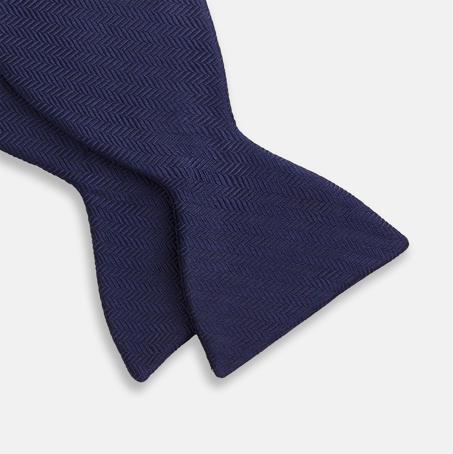 View 3 of product The Turnbull & Asser HERRINGBONE NAVY BOW TIE features a subtle herringbone pattern in navy blue, shown against a plain white background—the perfect accessory to elevate any smart look.