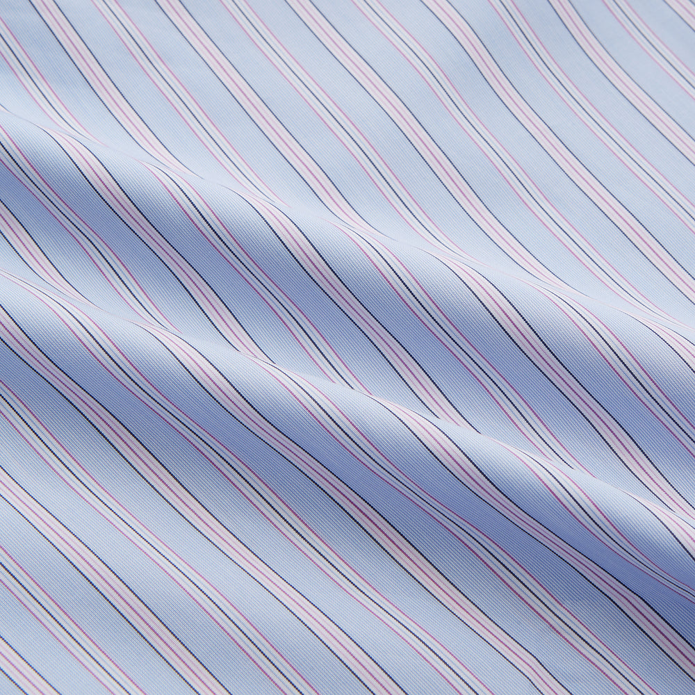 The Blue and Pink Stripe Poplin Cotton Nightshirt by Turnbull & Asser features long sleeves, a collar, front buttons, chest pocket, rounded hem, and light blue fabric with white, pink, and yellow vertical stripes.