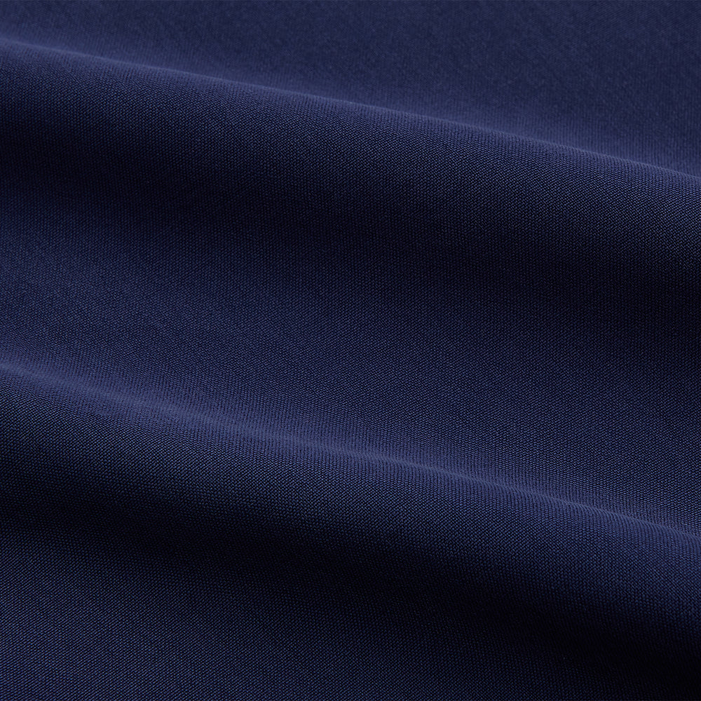 The Turnbull & Asser Blue Soft-touch Silk Lauren Shirt is a navy, long-sleeve button-up with an Igret stand collar, white buttons, curved hem, relaxed fit, and elongated body for a modern look, shown laid flat on a white background.