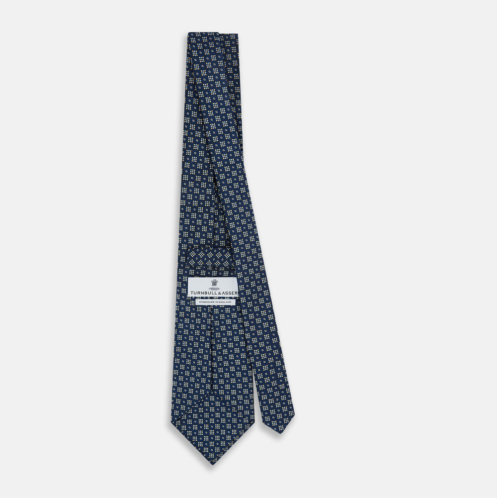 The Navy Diamond Silk Tie by Turnbull & Asser features a British-inspired geometric diamond pattern with small yellow and white squares against a navy silk background.