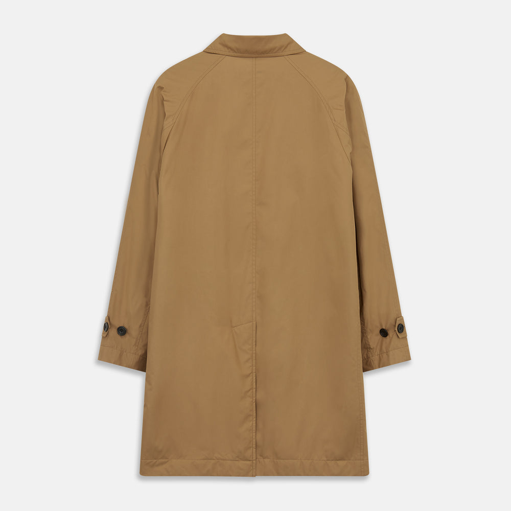 A person wears the Turnbull & Asser Camel Quintern Sealup Raincoat with Detachable Liner, paired with dark pants, standing against a plain light gray background, showing the sleek technical rainwear style with one hand in a pocket.