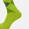View 4 of product The Lime Check Mid-Length Sock by Turnbull & Asser features a green and yellow argyle pattern with a ribbed cuff, crafted from comfortable cotton material, and is shown on a plain light background.