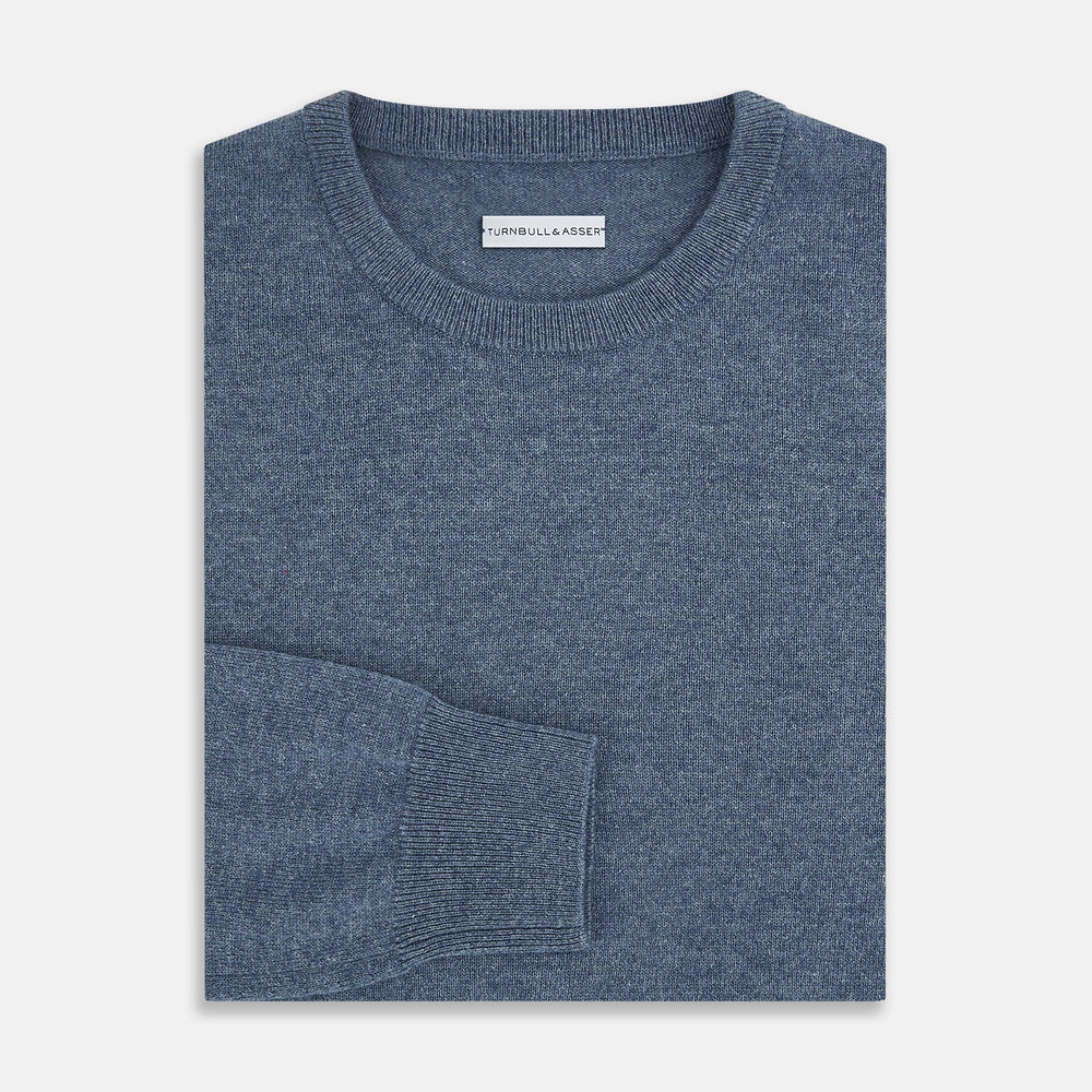 The Turnbull & Asser Pacific Blue Cashmere Round Neck Jumper features long sleeves and ribbed cuffs, hem, and neckline, shown on a light grey background.