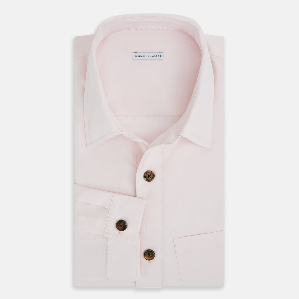 The Soft Pink Hyde Overshirt by Turnbull & Asser features long sleeves, sanforised cotton, dark buttons, and a left front pocket, shown laid flat on a white background.