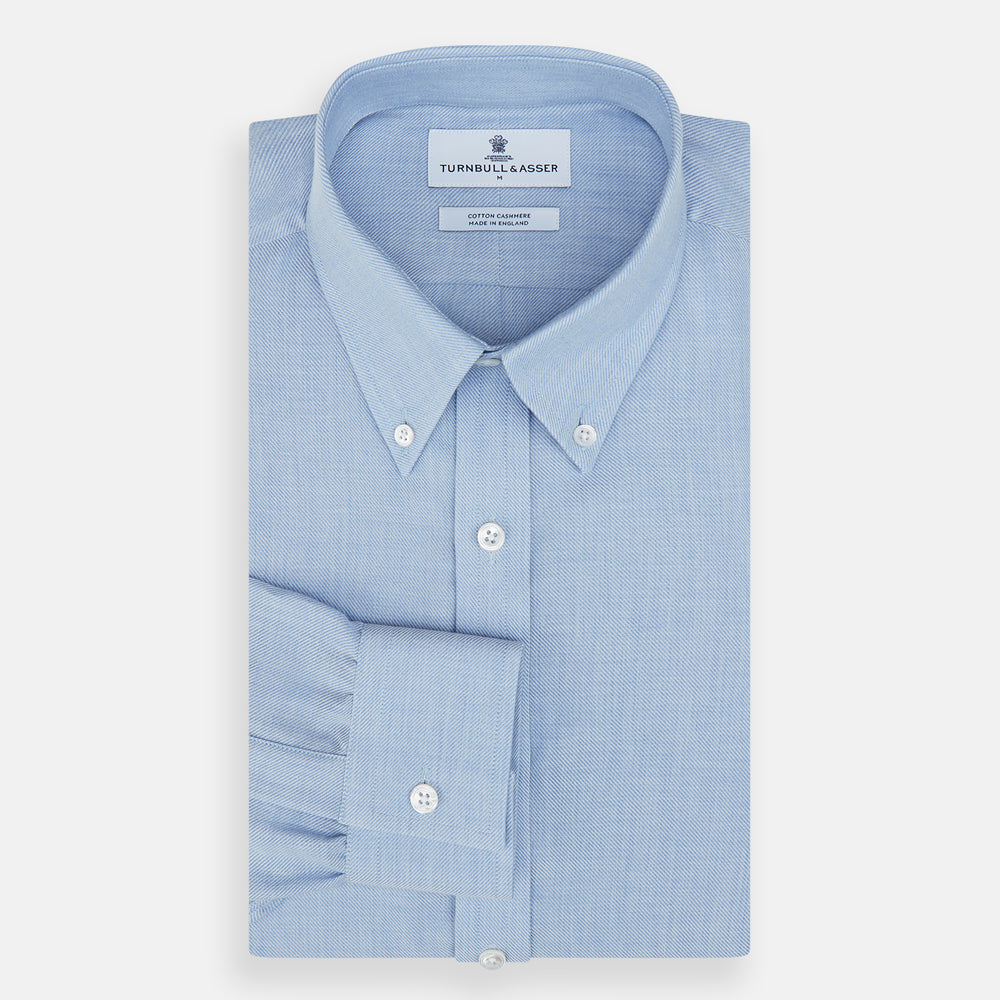 The Turnbull & Asser Pale Blue Cotton Cashmere Dorset Collar Richmond Shirt features long sleeves, a button-down collar, white buttons, and a chest pocket. It is neatly displayed flat on a white background.