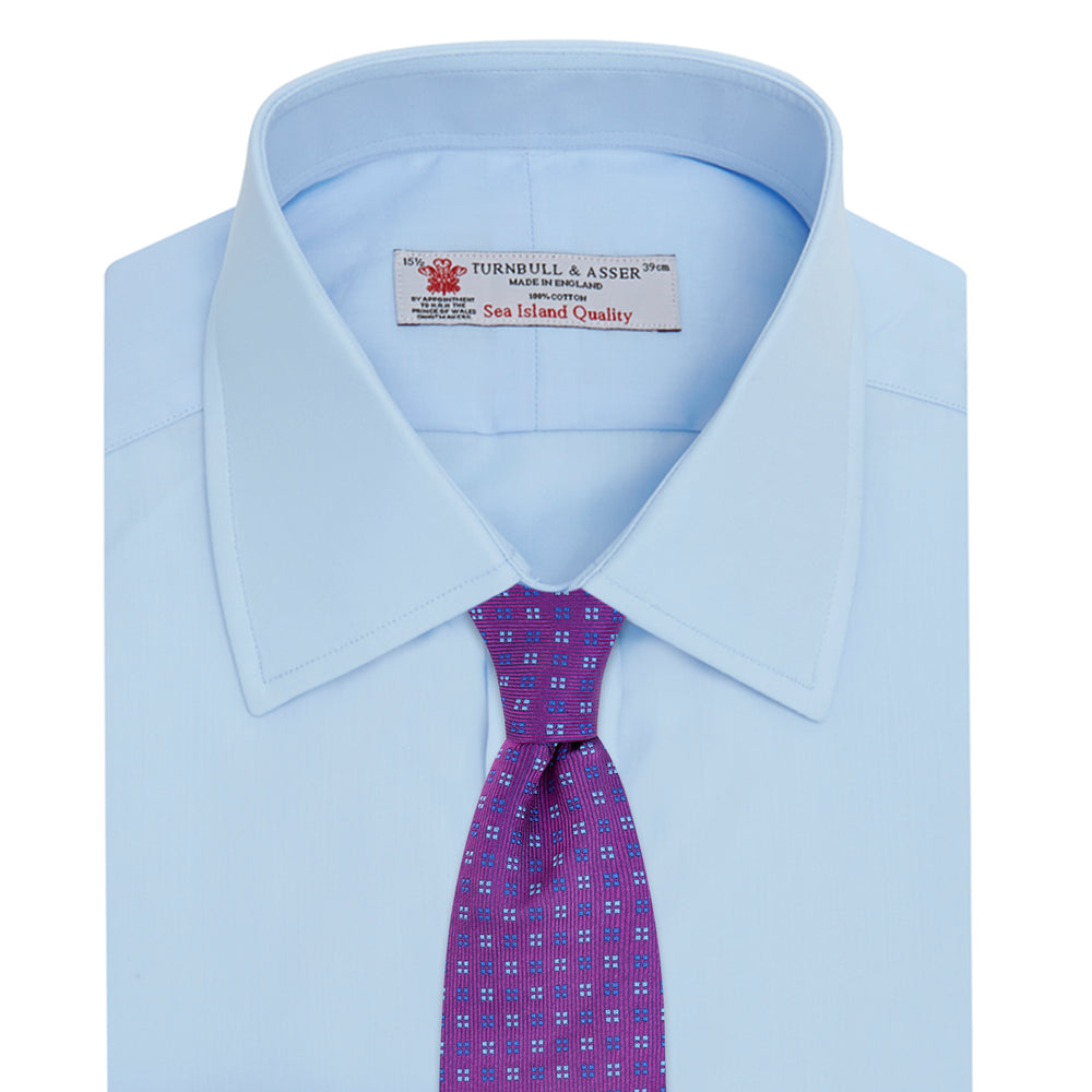 The Turnbull & Asser Light Blue Sea Island Quality Cotton Shirt features a T&A collar, double cuffs, white buttons, and a quality label inside the collar. Displayed on a plain white background.