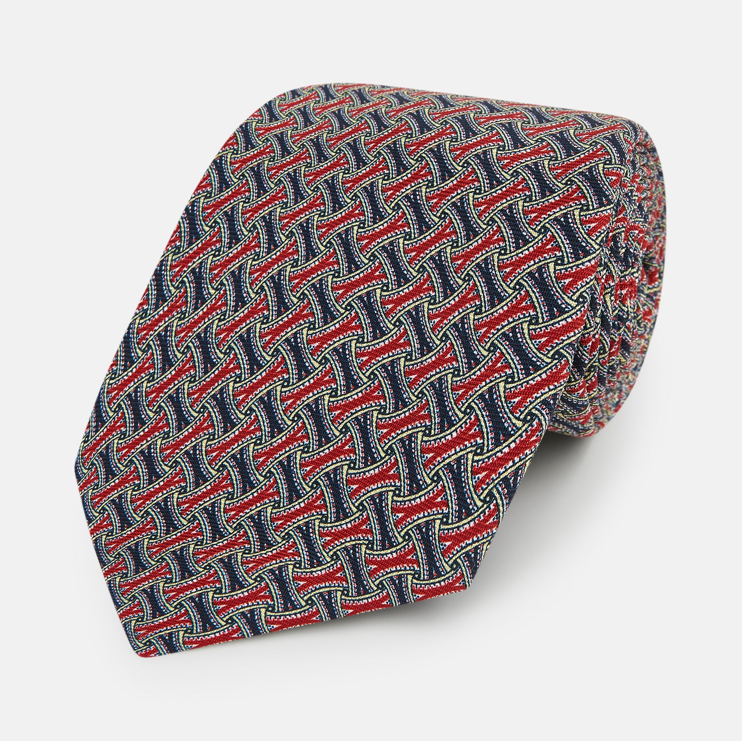View 1 of product A close-up of the Turnbull & Asser Red and Navy Weave Patterned Silk Tie, showcasing its geometric design in red, blue, white, and yellow on a white background.