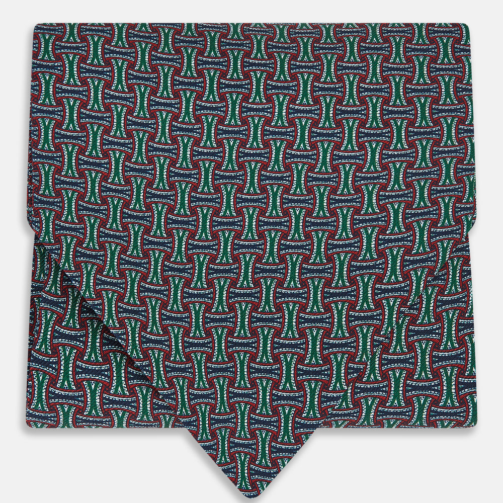 The Forest Green and Red Weave Patterned Silk Cravat by Turnbull & Asser features an elegant geometric design in rich hues, folded to a pointed end for a classic, British-inspired look.