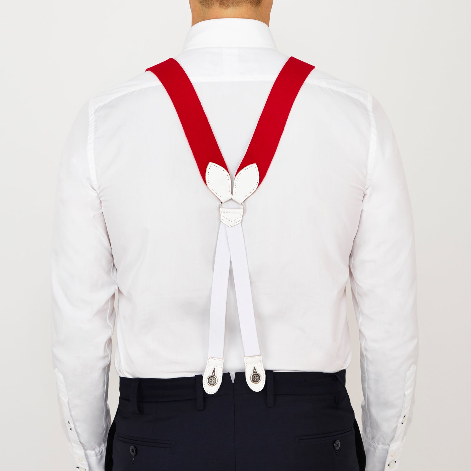 View 4 of product Two Red Adjustable Felt Braces by Turnbull & Asser, featuring white leather ends and silver-tone clasps, made in England from classic boxcloth, are laid flat on a white background.