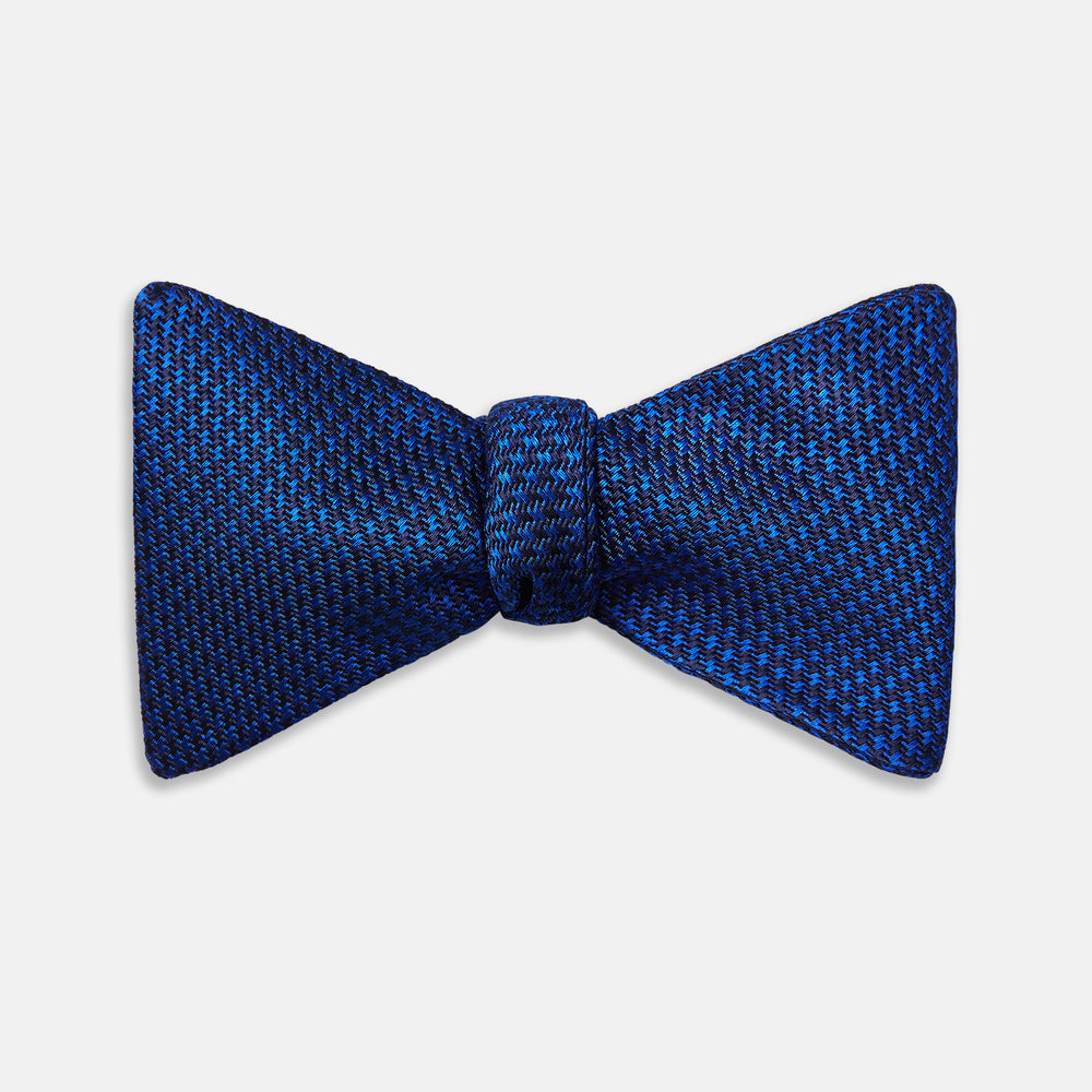 The HOUNDSTOOTH NAVY CRUISE BOW TIE by Turnbull & Asser features a refined textured pattern in blue, neatly tied and set against a white background—a stylish, versatile accessory for the modern gentleman.