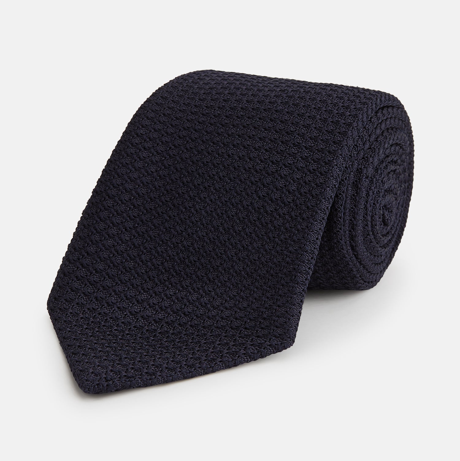 View 1 of product The GRENADINE NEW NAVY TIE by Turnbull & Asser features a dark navy blue woven texture, making it the perfect accessory for refined looks. Displayed against a plain white background.