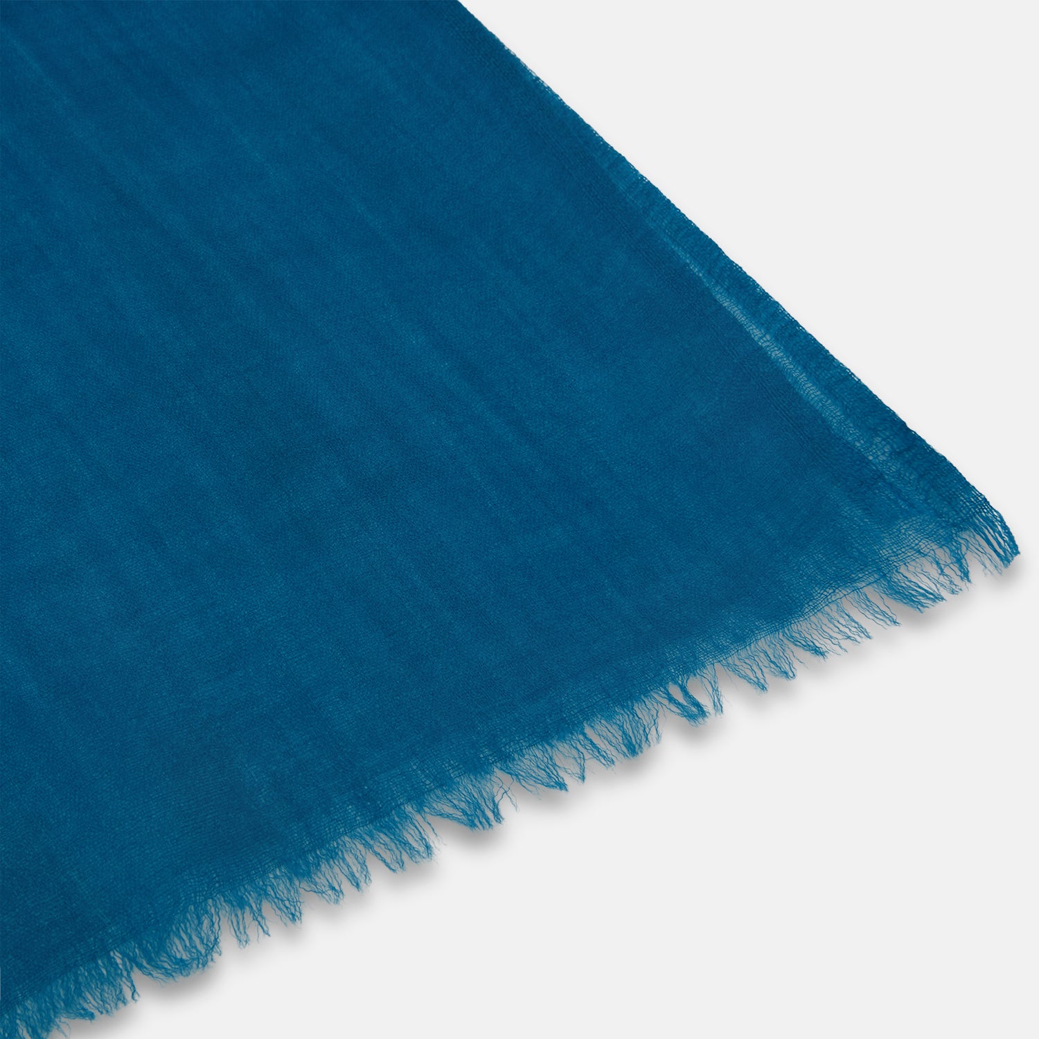 View 2 of product The Turnbull & Asser Steel Blue Cashmere Scarf, featuring a soft texture and slightly frayed edges, is neatly folded and tied in a loose knot against a white background.