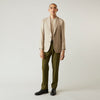 View 3 of product A man wearing the Beige Wool, Silk and Cashmere Bern Jacket by Turnbull & Asser over a matching shirt and olive green pants stands against a plain light gray background, looking to his left with a neutral expression.