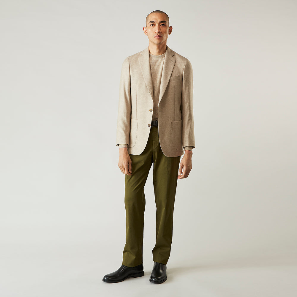 A man wearing the Beige Wool, Silk and Cashmere Bern Jacket by Turnbull & Asser over a matching shirt and olive green pants stands against a plain light gray background, looking to his left with a neutral expression.