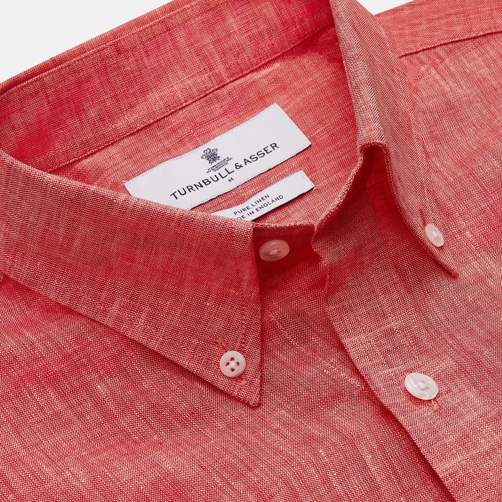 View 2 of product The Turnbull & Asser Pink Linen Weekend Fit Hayne Shirt is a casual, long-sleeve button-down with a subtle texture and white buttons, neatly laid flat on a white background.