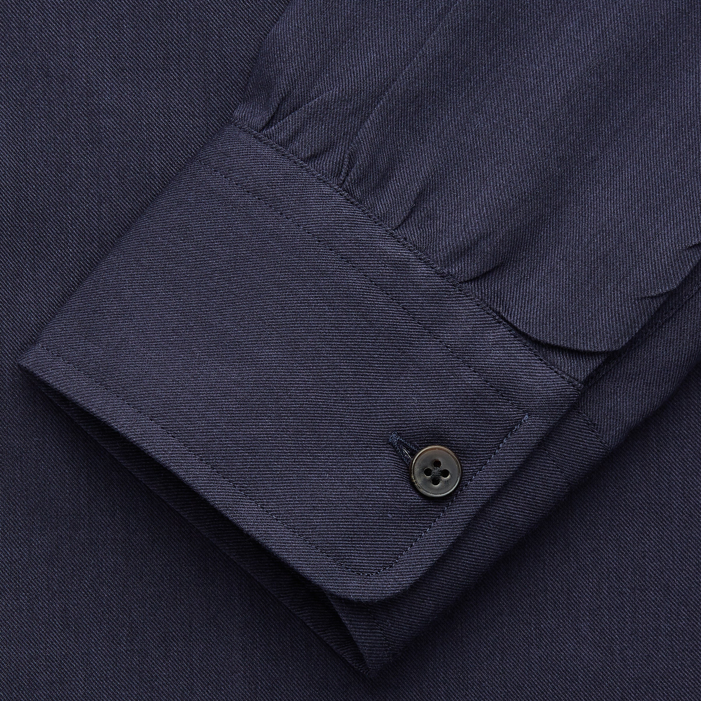 View 3 of product The Turnbull & Asser Navy Military Weekend Fit Shirt features a stand collar, black buttons, dual chest flap pockets, and 1-button cuffs in Italian cotton-wool, shown laid flat on a white background.