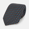 View 1 of product The Turnbull & Asser Navy and Orange Geometric Motif Silk Tie features a dark blue base with small orange, white, and light blue geometric patterns—a refined statement of British craftsmanship.