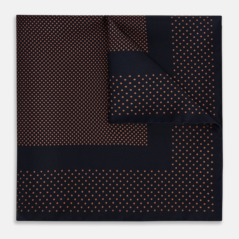 The Navy and Blush Dot Silk Pocket Square by Turnbull & Asser features a navy base with small orange polka dots and a border, shown neatly folded with one corner flipped over.