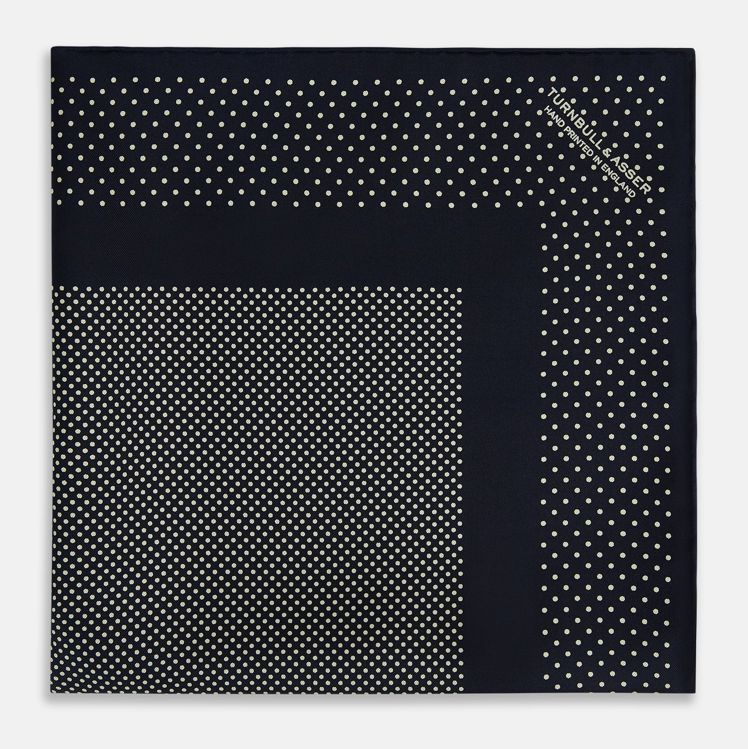 View 3 of product The Turnbull & Asser Navy and Cream Dot Silk Pocket Square features small cream dots, a border design, and displays handmade craftsmanship with one corner folded to show the reverse side.