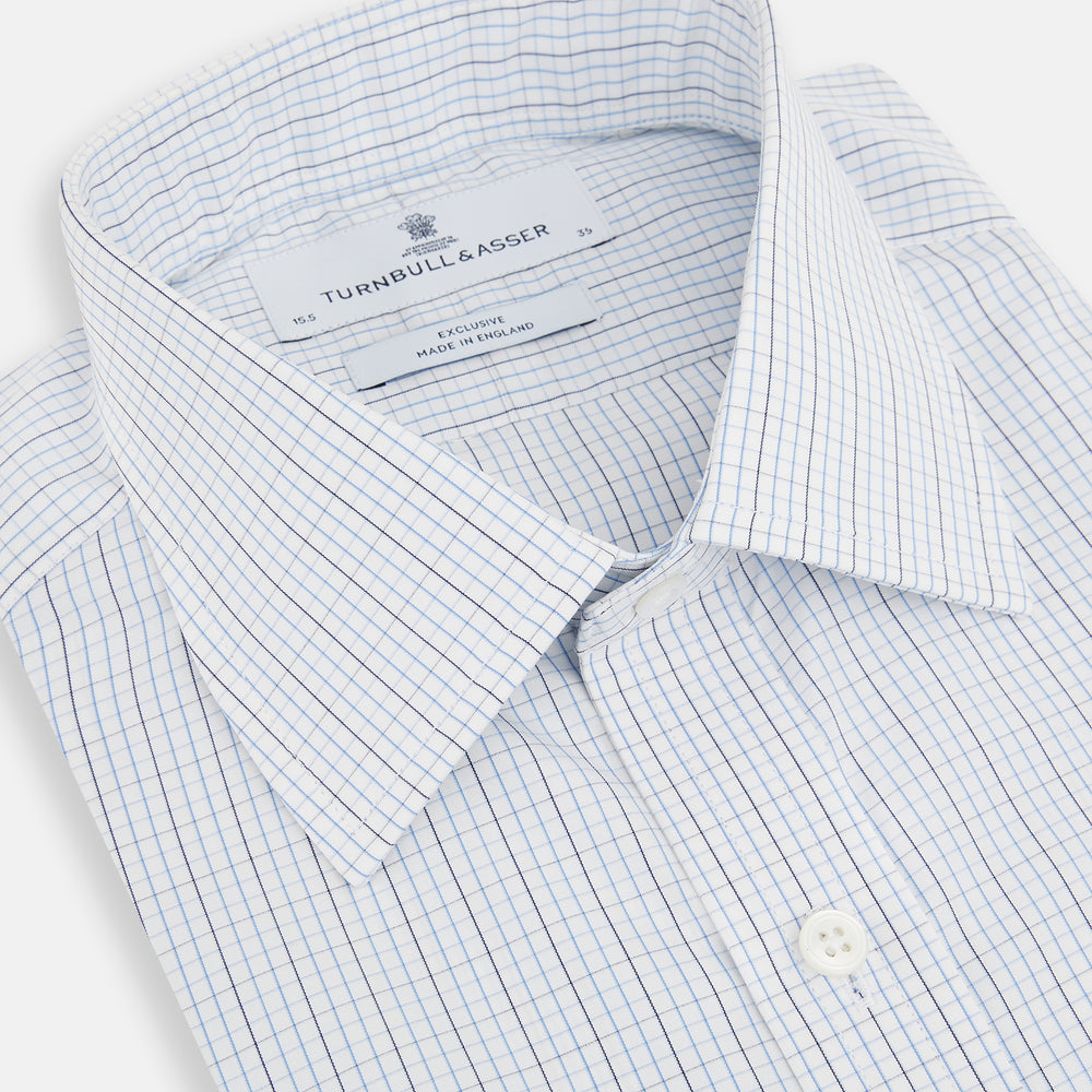 The Turnbull & Asser Pale Blue and Navy Grid Check Mayfair Shirt is a long-sleeve, button-up shirt made from fine Italian cotton, featuring a pointed collar and buttoned cuffs, shown against a plain white background.