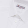View 5 of product A Turnbull & Asser Two-Fold 200 White Cotton Shirt with T&A collar and double cuffs, neatly folded to show the label inside the collar, is displayed on a light blue background.