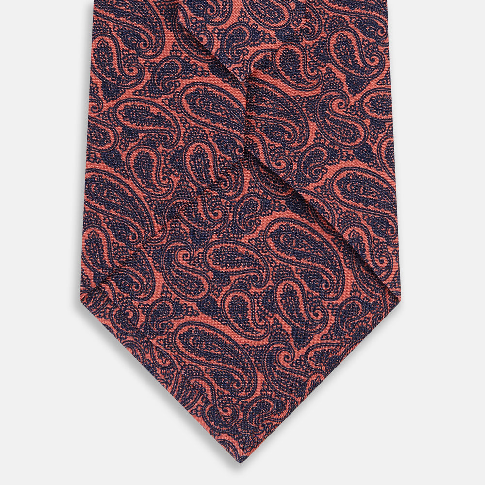 A rolled-up Turnbull & Asser Orange Paisley Silk Tie, featuring an elegant pattern, is displayed against a plain white background.