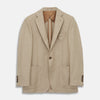 View 2 of product A man wearing the Beige Wool, Silk and Cashmere Bern Jacket by Turnbull & Asser over a matching shirt and olive green pants stands against a plain light gray background, looking to his left with a neutral expression.
