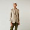 View 1 of product A man wearing the Beige Wool, Silk and Cashmere Bern Jacket by Turnbull & Asser over a matching shirt and olive green pants stands against a plain light gray background, looking to his left with a neutral expression.