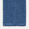 View 4 of product The Turnbull & Asser Knitted Mid Blue Silk Plain Tie features a textured knit and is shown rolled up on a plain white background—a refined accessory that pairs perfectly with formal shirts.