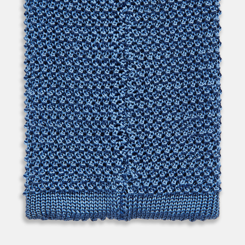 The Turnbull & Asser Knitted Mid Blue Silk Plain Tie features a textured knit and is shown rolled up on a plain white background—a refined accessory that pairs perfectly with formal shirts.