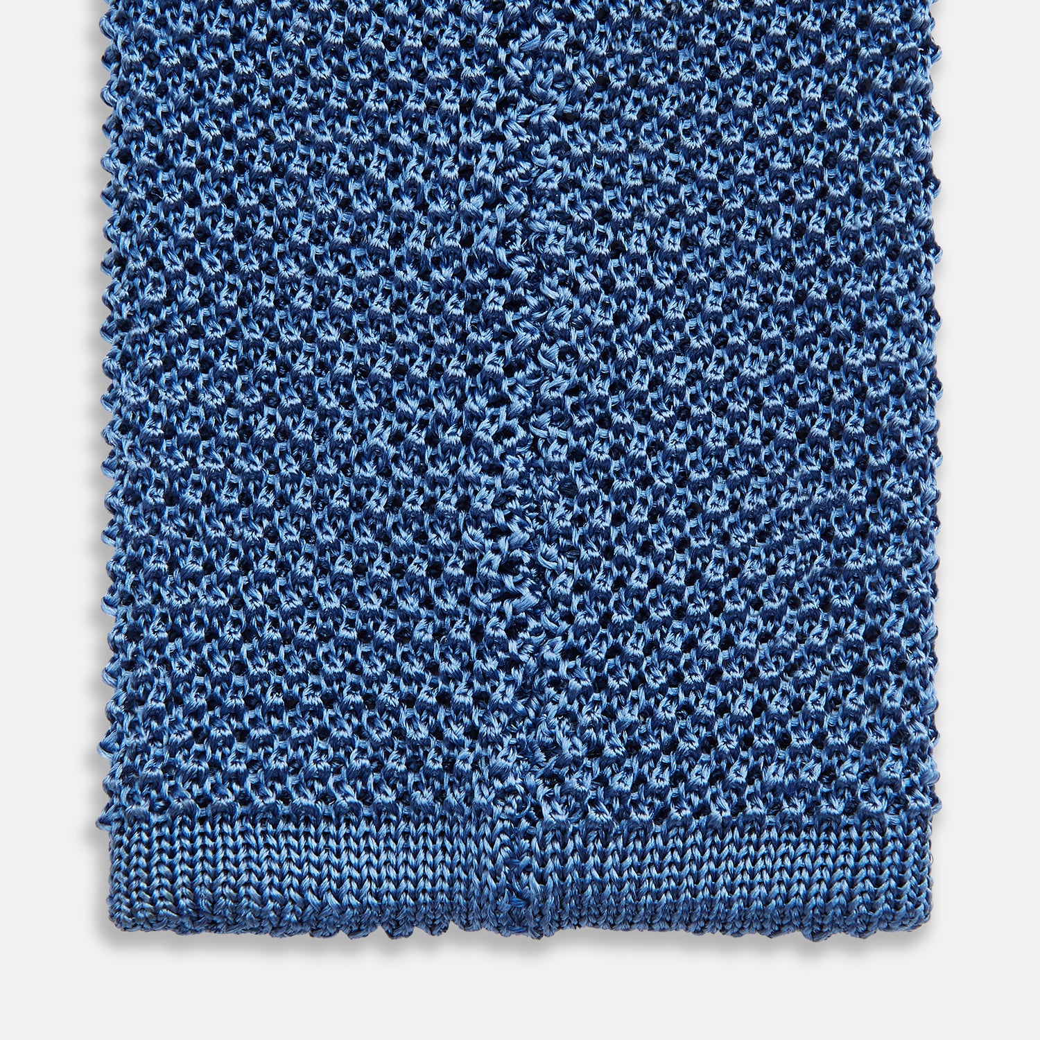 View 4 of product The Turnbull & Asser Knitted Mid Blue Silk Plain Tie features a textured knit and is shown rolled up on a plain white background—a refined accessory that pairs perfectly with formal shirts.