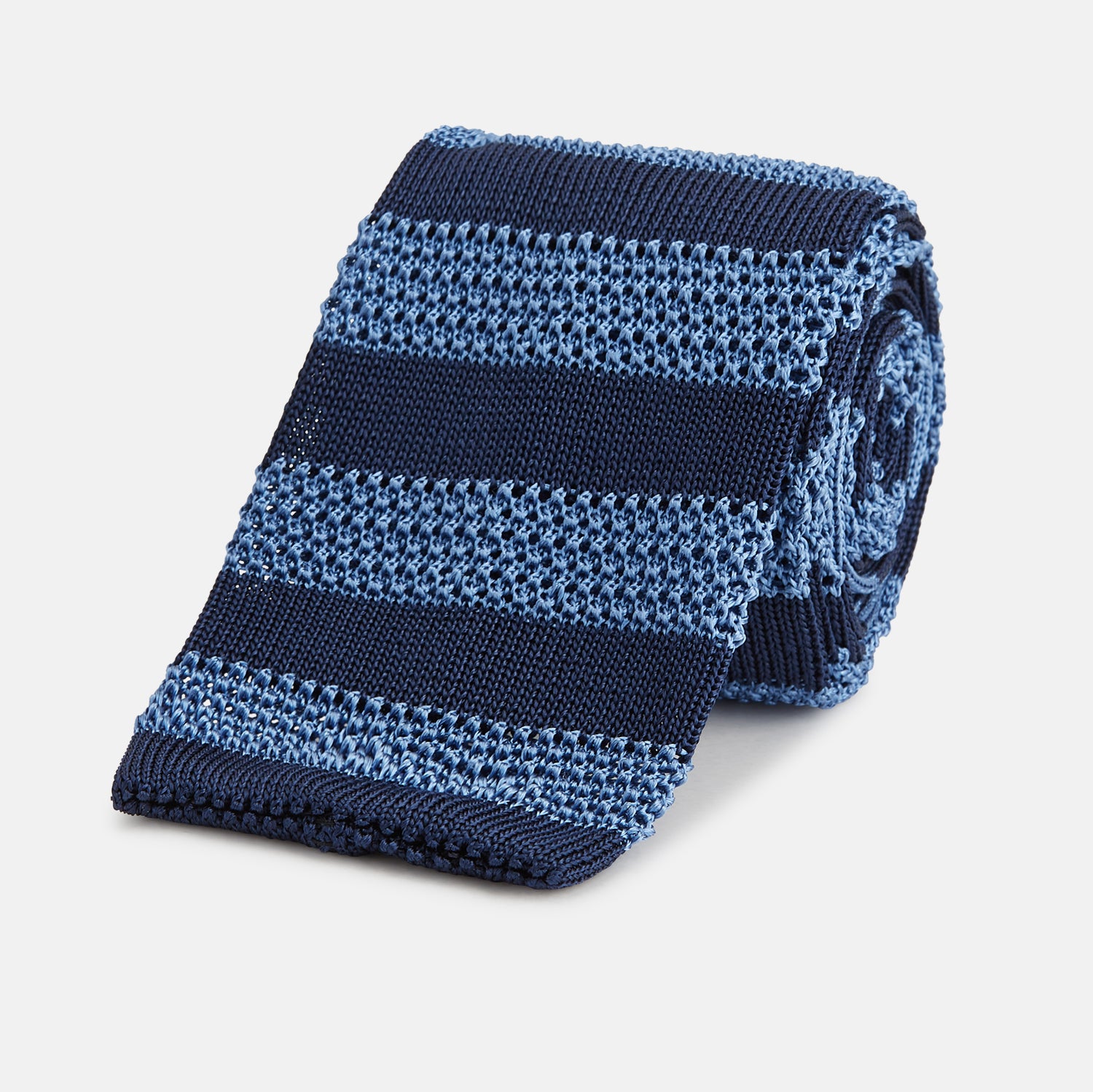 View 1 of product The Turnbull & Asser Navy and Blue Square tipped knitted tie features horizontal stripes and a rolled-up silk design, elegantly displayed on a plain white background.