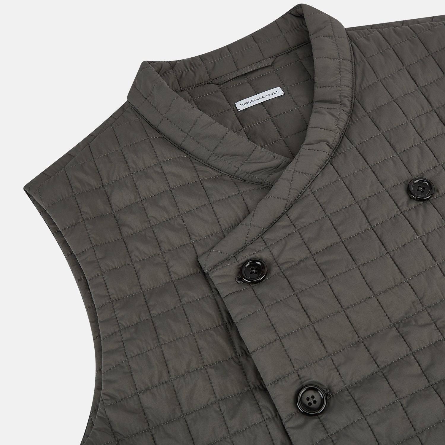 View 2 of product The Turnbull & Asser Shadow Grey Double-Breasted Quilted Gilet features a sleeveless design, asymmetrical collar, side zip pockets, slanted chest pocket, grid pattern, and modern black buttons—perfect for layered dressing.