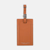 View 1 of product The Brown Leather Luggage Tag by Turnbull & Asser features textured brown leather, a silver buckle strap, and the Turnbull & Asser name embossed in silver at the bottom.
