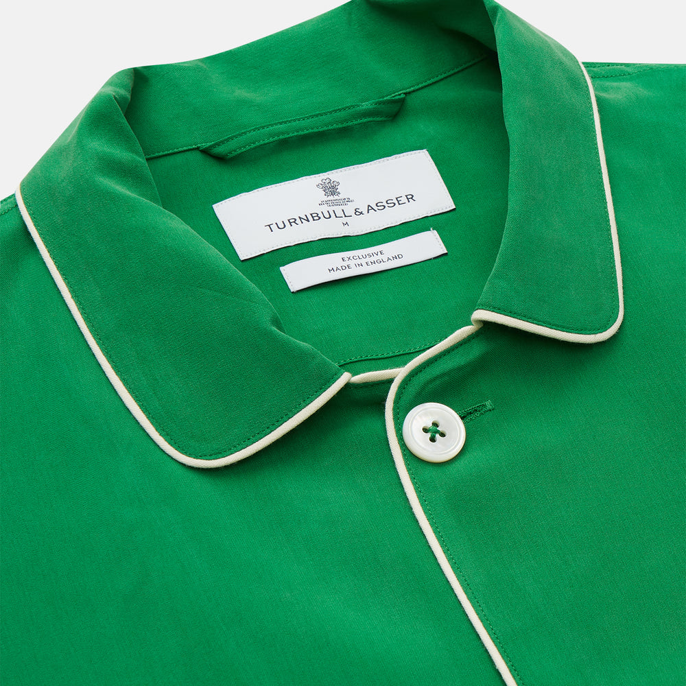 The Turnbull & Asser Green Silk Hyde Pyjamas Set features a long-sleeve button-up top with three pockets and modern fit elastic waistband pants in silk blend, both shown laid flat on a white background.