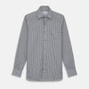 View 2 of product A person with a shaved head models the Turnbull & Asser Grey Check Weekend Fit Flannel Shirt with a Derby collar and 1-button cuffs, sleeves rolled up, paired with dark trousers against a plain background, gazing directly at the camera.