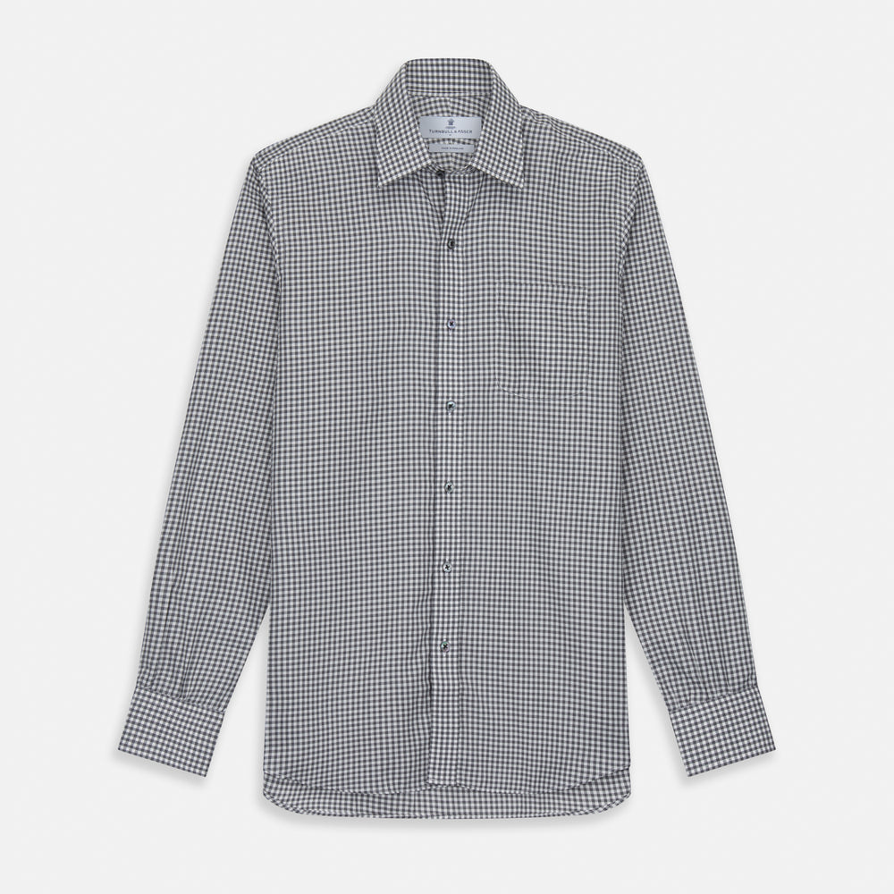 A person with a shaved head models the Turnbull & Asser Grey Check Weekend Fit Flannel Shirt with a Derby collar and 1-button cuffs, sleeves rolled up, paired with dark trousers against a plain background, gazing directly at the camera.