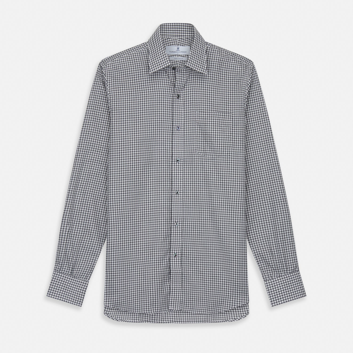 View 2 of product A person with a shaved head models the Turnbull & Asser Grey Check Weekend Fit Flannel Shirt with a Derby collar and 1-button cuffs, sleeves rolled up, paired with dark trousers against a plain background, gazing directly at the camera.