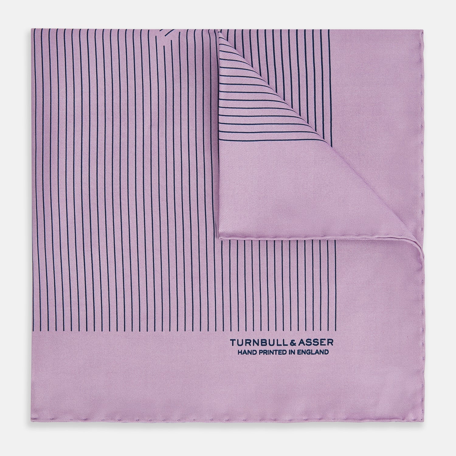 View 1 of product The Lilac Stripe Silk Pocket Square by Turnbull & Asser features thin vertical navy stripes on folded silk, with "TURNBULL & ASSER HAND PRINTED IN ENGLAND" inscribed in the bottom right corner, reflecting British heritage.