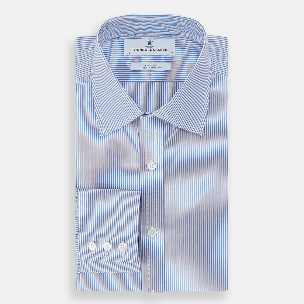 The Turnbull & Asser Pale Blue Pinstripe Mayfair Shirt features pale blue pinstripes, a classic T&A collar, white buttons, and cuffed sleeves, shown against a plain white background.