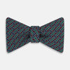 View 1 of product The Forest Green and Red Weave Patterned Silk Bow Tie by Turnbull & Asser features interwoven red, blue, and forest green lines with white dotted accents in a geometric design on a dark background.