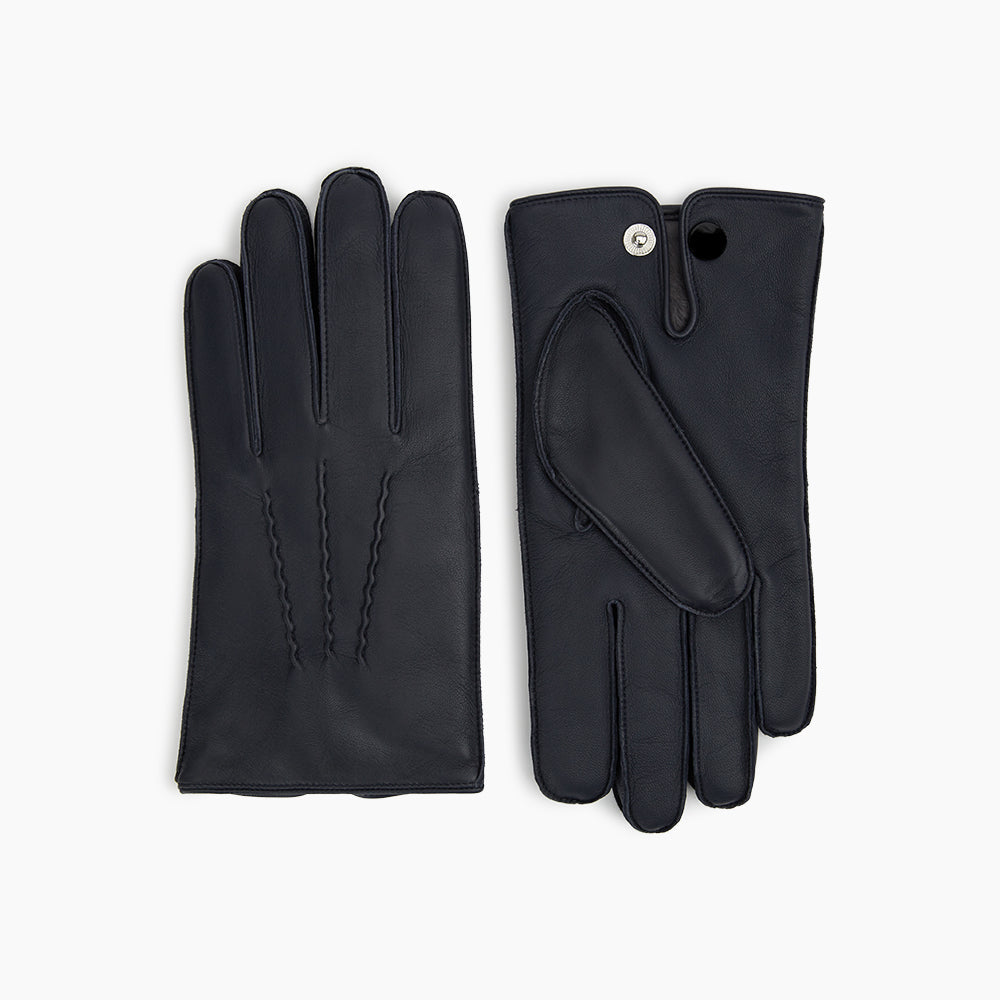 A pair of Turnbull & Asser Navy/Grey Fur-Lined Hairsheep Leather Touchscreen Gloves is displayed on a light background, with one glove showing the palm and the other the back, both featuring simple stitched details and a wrist button closure.