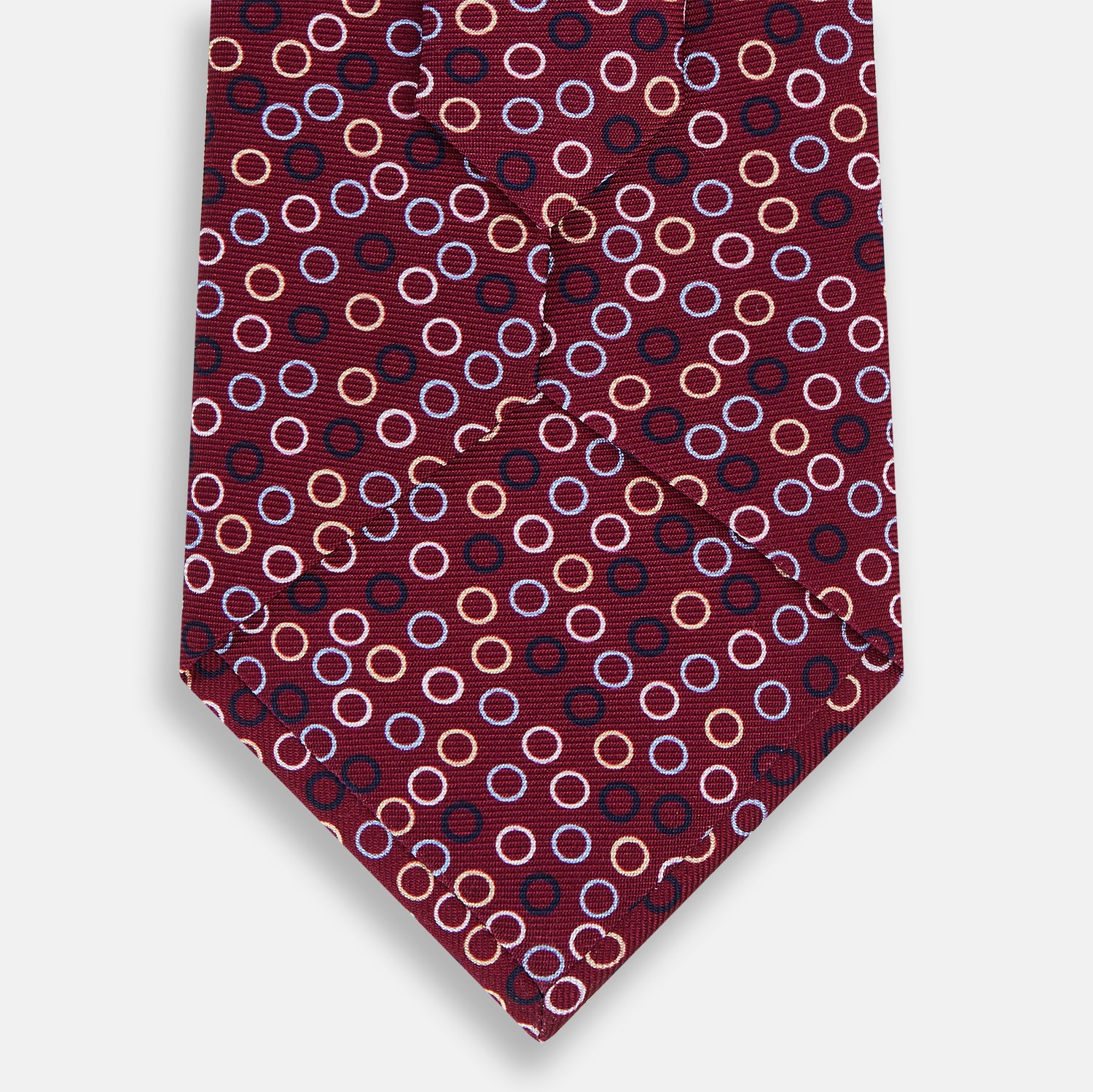 View 3 of product The Turnbull & Asser Pink and Navy Circle Burgundy Silk Tie features a rolled burgundy silk design with small, evenly spaced white, pink, and light blue circle patterns.
