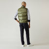 View 4 of product A man stands against a plain background wearing the Turnbull & Asser Green Peyton Sealup Quilted Gilet over a striped shirt, dark trousers, and white sneakers, with his hands in his pockets and looking slightly to the side.