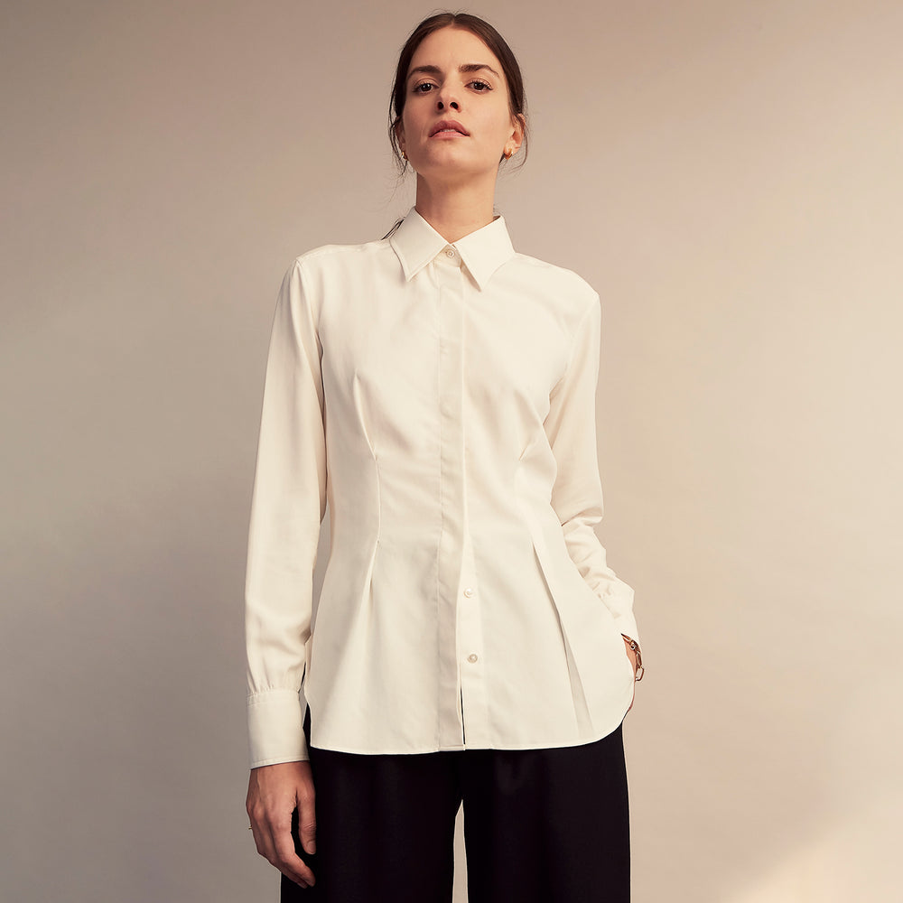 The Cream Silk Tailored Bianca Shirt by Turnbull & Asser features long sleeves, a pointed collar, and curved hem in soft-touch peace silk with a tailored fit. Shown laid flat on a white background.