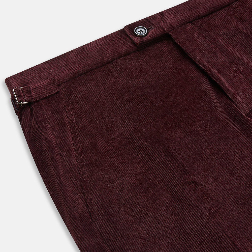 The Turnbull & Asser Burgundy Corduroy Henry Trousers feature a straight-leg cut, button and zip closure, and adjustable side tabs—perfect for refined formalwear—shown here on a plain white background.