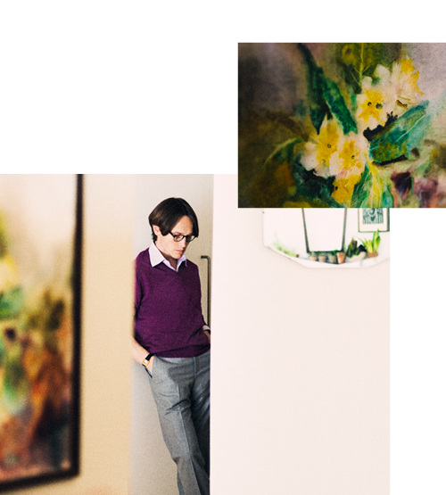 A person in a purple sweater vest and glasses leans against a wall, looking down. Above them, there is a small painting of yellow and white flowers with green leaves. The background is mostly white.