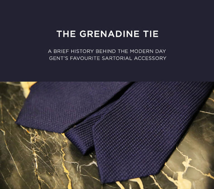 A close-up of two dark blue grenadine ties placed on a black marble surface, with text above reading “The Grenadine Tie: A brief history behind the modern day gent’s favourite sartorial accessory.”.
