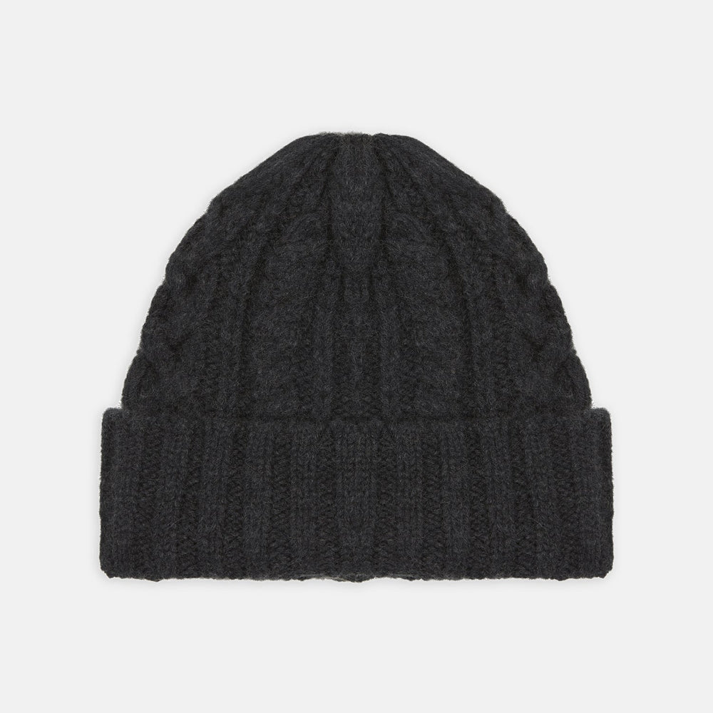 The Turnbull & Asser Charcoal Cable Knit Cashmere Hat features a ribbed fold-over cuff and textured pattern, ideal for winter, shown laid flat on a white background.